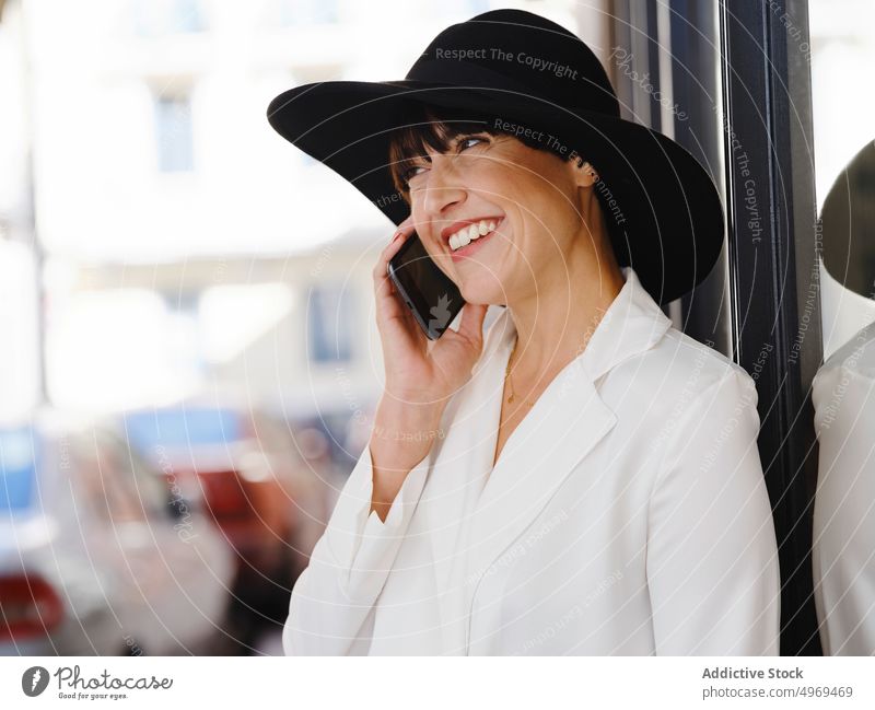 Elegant woman in hat talking on smartphone in city charming elegant speak street style using trendy female high heels building mobile device gadget communicate