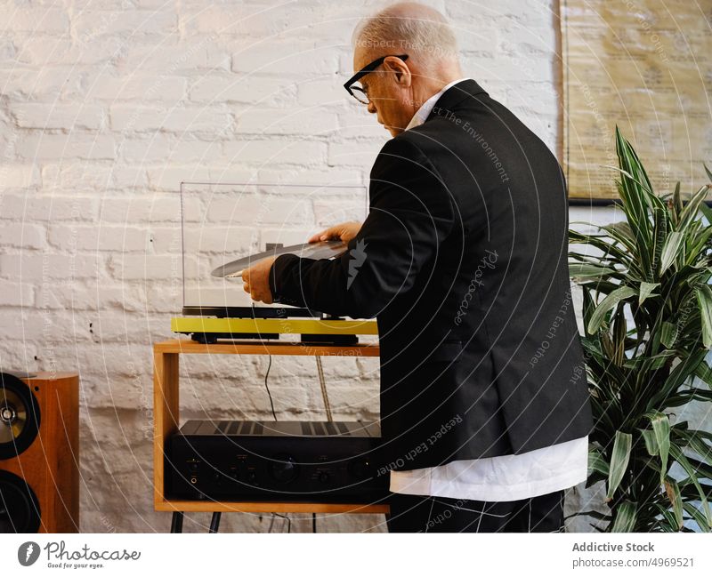 Aged man putting vinyl record into record player music aged disc nostalgia senior listen retro elegant male hobby enjoy tune jacket vintage audio melody sound