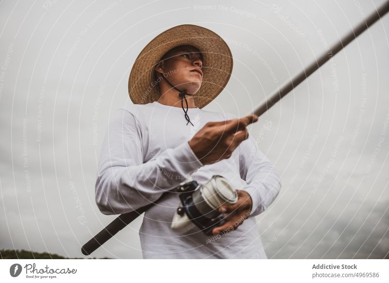 Man fishing on seashore fisherman rod coast hobby equipment catch leisure male seaside hat angler skill water lifestyle rest free time guy environment nature