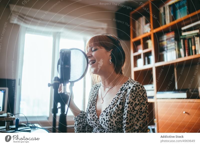 Singer performing song into microphone at home singer record music headset professional producer using gadget woman empty focus vocalist brace enjoy leopard