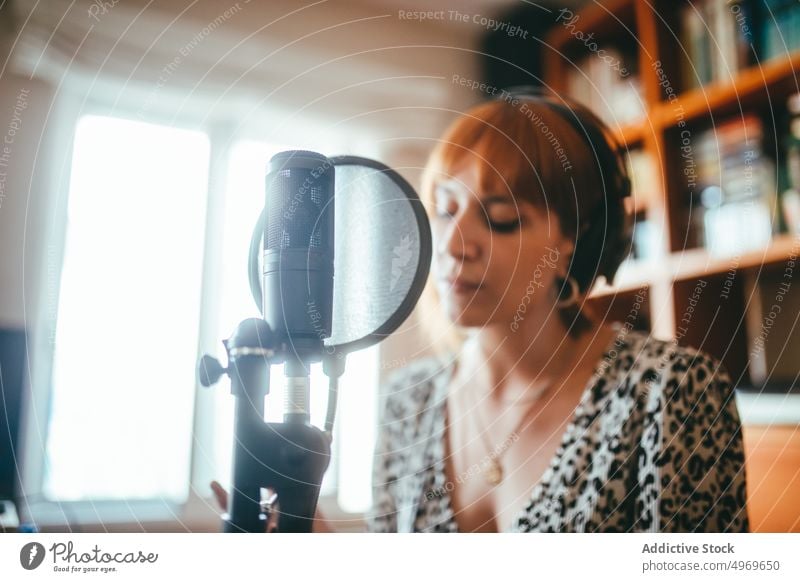 Singer performing song into microphone at home singer record music headset professional producer using gadget woman empty focus vocalist brace enjoy leopard