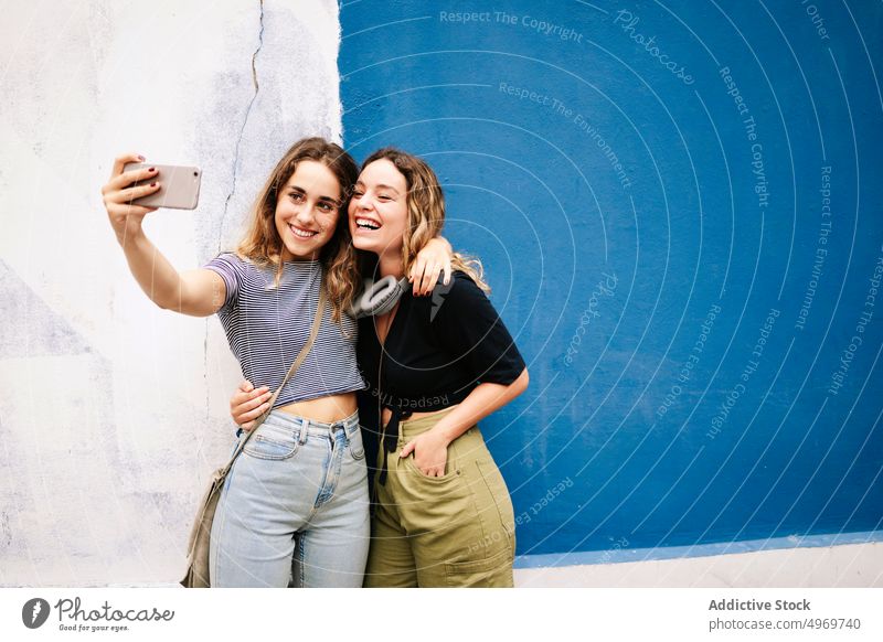 Women taking selfie on smartphone women picture hugging photo camera using street meeting friendship photography walking bonding device gadget cheerful casual