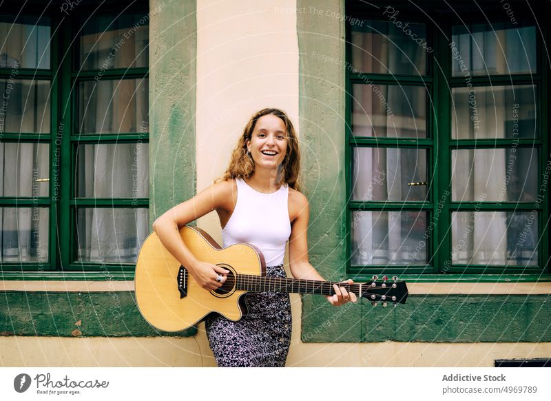Curly woman playing guitar leaning on the wall music romantic young instrument cheerful female musical fun vacation fashion holiday casual summer creative