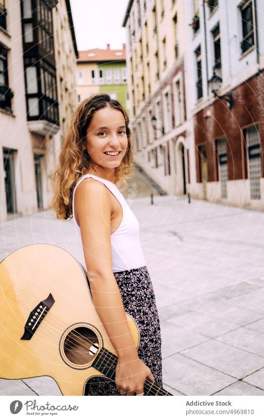 Charming curly woman with a guitar and looking at camera music romantic young play instrument cheerful female musical fun vacation fashion holiday casual summer