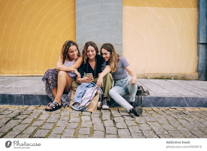 Women browsing smartphone nearby colorful wall women street meeting using friendship cheerful casual smiling together mobile connection communication gadget