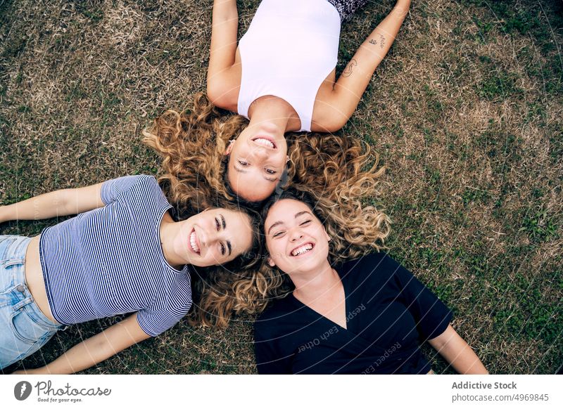 Relaxed girl friend lying in grass with heads in circle and laug women park friends lawn happy friendship smile together cheerful attractive fun group joyful
