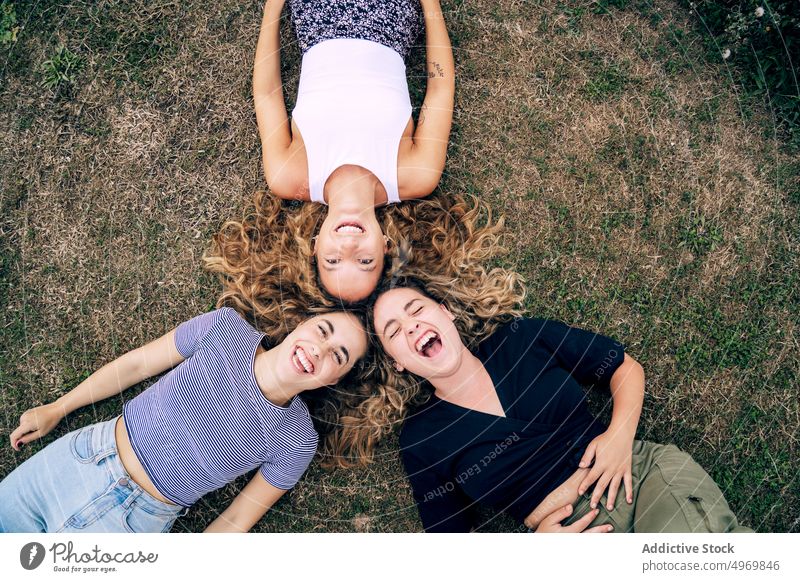 Relaxed girl friend lying in grass with heads in circle and laug women park friends lawn happy friendship smile together cheerful attractive fun group joyful