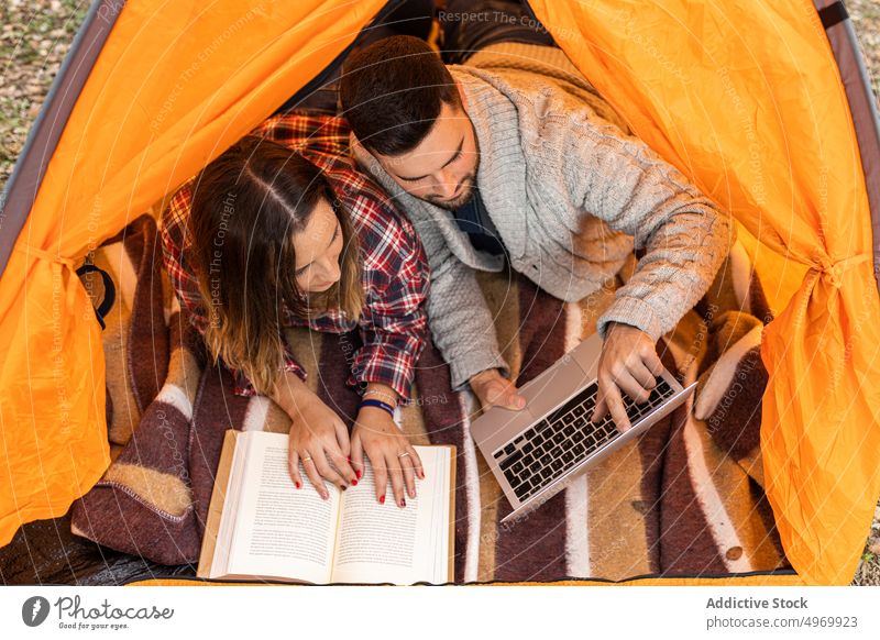 Camping couple drinking hot beverage inside tent camp enjoy grass outdoor relax forest holidays boyfriend adventure field together countryside read vacation