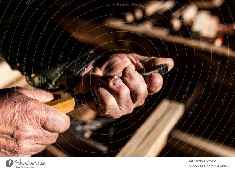 Crop elderly carpenter with chisel workshop hands wrinkled equipment tool industry craft woodworker male senior mature manual job business carver instrument