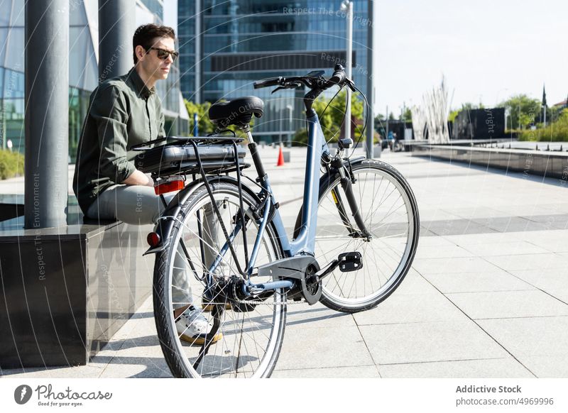 Trendy man sitting with bike in downtown city bicycle urban street parked style vehicle megapolis male modern center transport trendy contemporary convenient