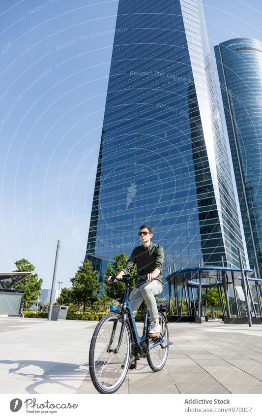 Stylish man riding bike in city center ride bicycle commute work summer urban street male modern businessman transport vehicle sunlight serious guy active