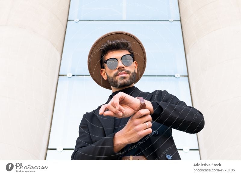 Masculine man in trendy sunglasses behind handrail in town fashion vogue style individuality creative design contemporary masculine hat jacket macho stylish