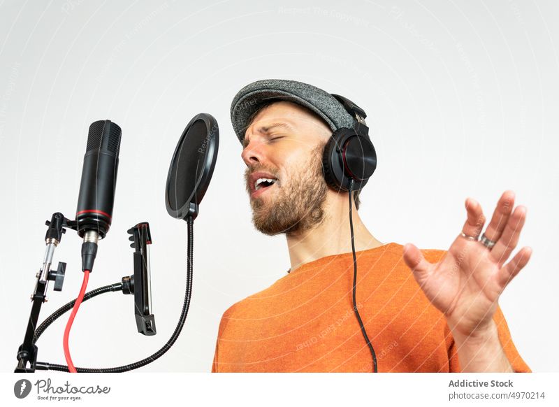 Talented man with smartphone recording song in studio sing microphone audio music voice cellphone mobile phone screen device gadget headphones appliance