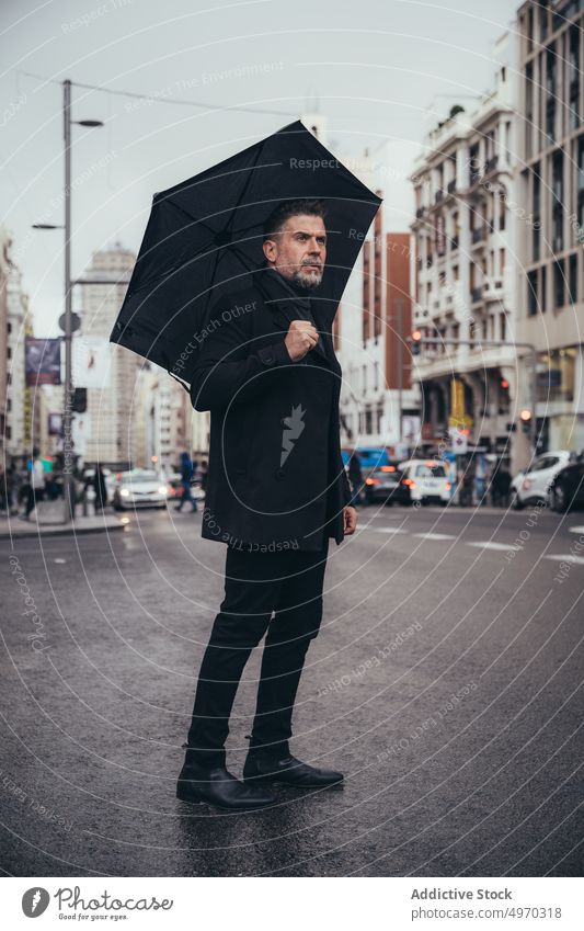 Thoughtful middle aged businessman with umbrella in street entrepreneur classy walk pavement rainy trendy city elegant urban autumn work modern male smart