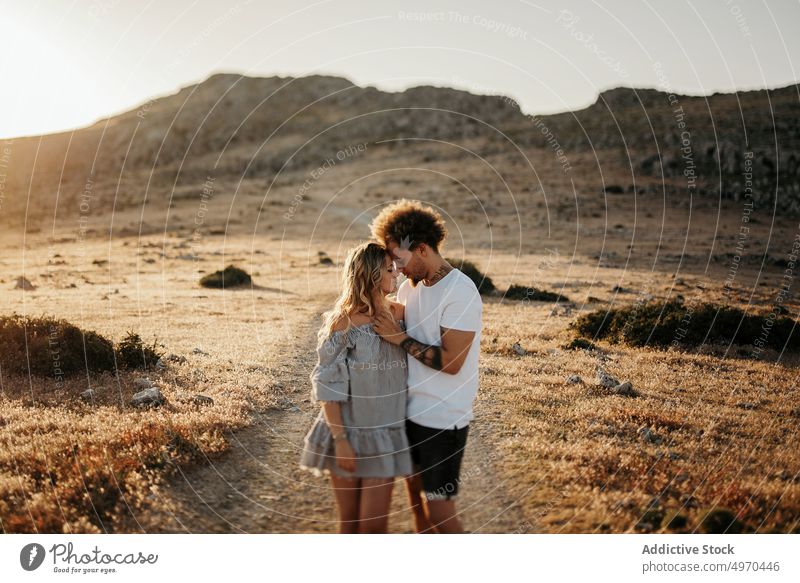 Cheerful adult couple embracing against highland during sunset embrace love sensual happy hill hipster romantic relationship romance affection girlfriend hug