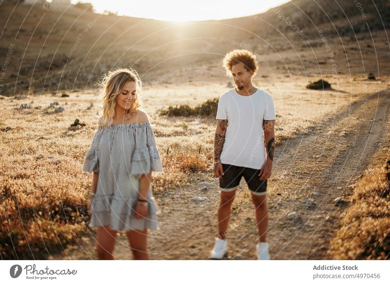Couple standing on footpath against rocky hill in evening couple walk romantic stroll love serious girlfriend boyfriend date weekend countryside relationship
