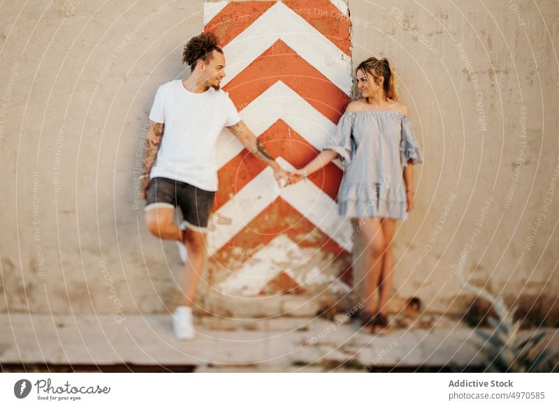 Crop couple holding hands against shabby wall love street city casual together modern man woman relationship summer relax lifestyle rest trendy town young