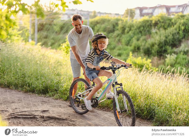 Father teaching his son how to ride a bicycle day healthy lifestyle active lifestyle outdoors fun joy cycling biking activity bike cyclist enjoying ecological