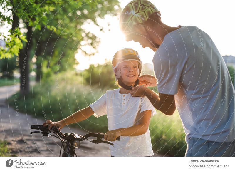 Shot of a father adjusting his son's helmet day healthy lifestyle active lifestyle outdoors fun joy bicycle cycling biking activity bike cyclist enjoying