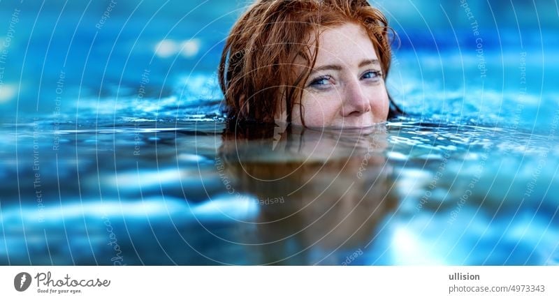 Pretty sexy, seductive, sensual redhead woman portrait relaxes swimming in turquoise, blue thermal bath hot water pool, happy smiling copy space pretty red hair
