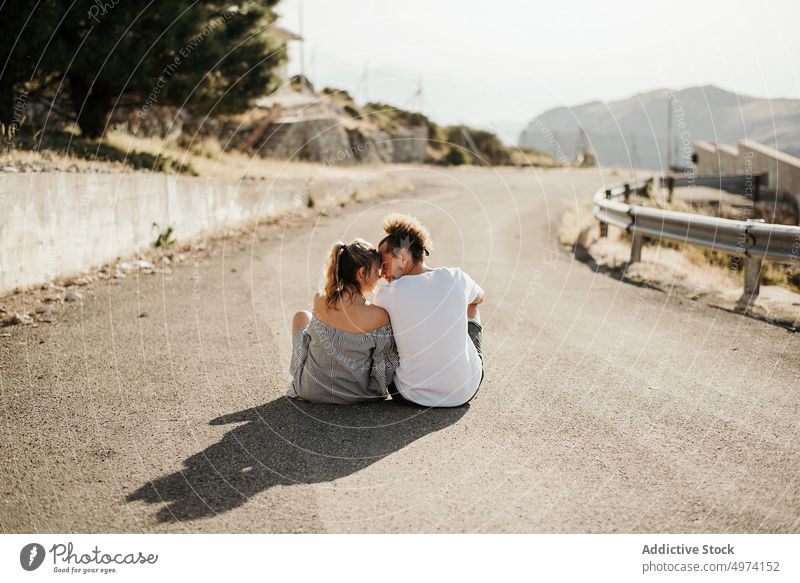 Happy adult couple enjoying each other while sitting on road in highland love girlfriend boyfriend hipster romantic tender sensual way relationship asphalt date
