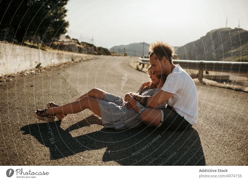 Young couple enjoying each other while sitting on road and embracing love hug hipster romantic sensual relationship happy street admire fondness girlfriend