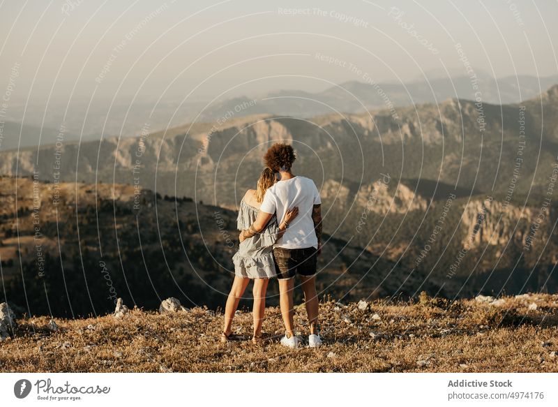Happy couple enjoying view of highland while standing on hill and hugging mountain travel romantic park tender relationship embrace idyllic tourism love