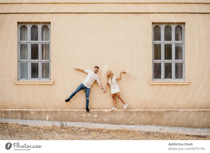 Happy young couple having fun on street exterior window relationship cheerful facade girlfriend boyfriend happy joy trendy building together urban smile town
