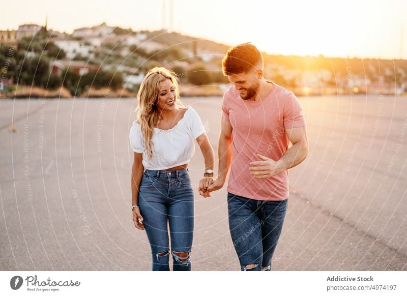 Young couple laughing together on street at dusk love happy hug relationship town girlfriend cheerful sunset excited tender care bonding boyfriend smile date