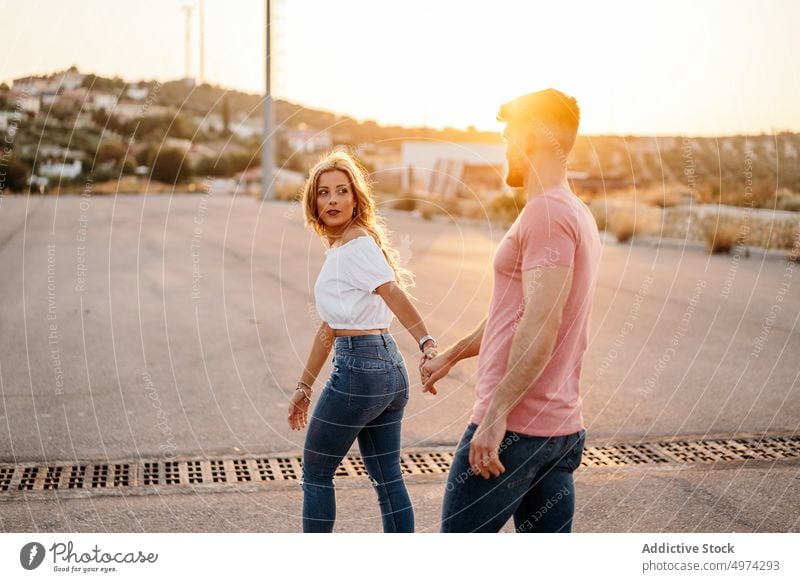 Young couple walking holding hands on street at dusk love happy hug relationship town girlfriend cheerful sunset excited tender care bonding boyfriend smile