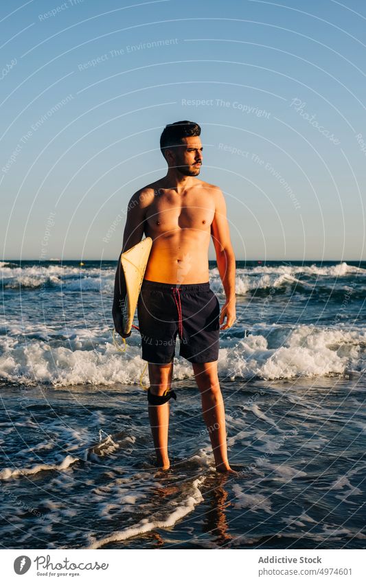 Young man standing on the beach with a surfboard surfer sun beauty water sea carrying freedom lifestyles sunrise wearing people sand sunlight vacations ocean
