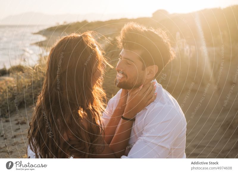 Loving couple hugging and looking at each other on seashore on sunset beach embracing in love sandy sunlit honeymoon happy lifestyle sensual romantic dating