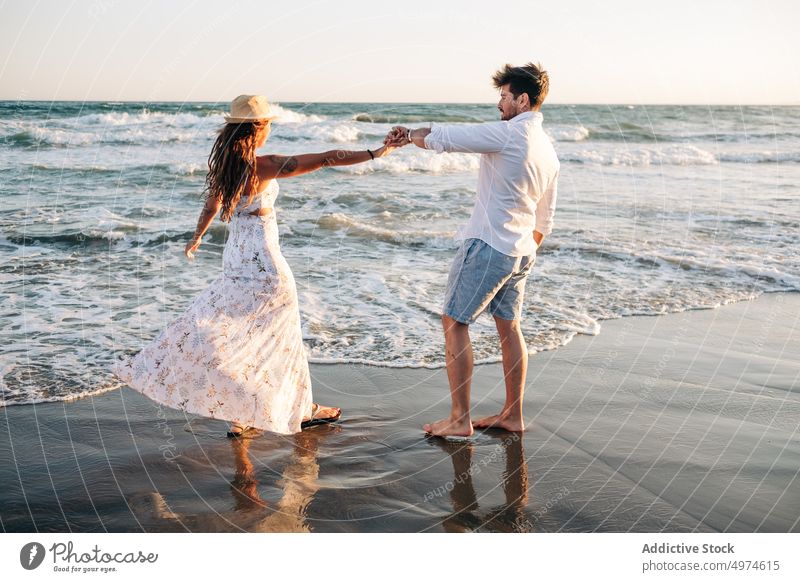 Affectionate couple standing on ocean waves holding hands on sunset sea summer in love sunlit enamored honeymoon intimacy amorous dating romantic tenderness