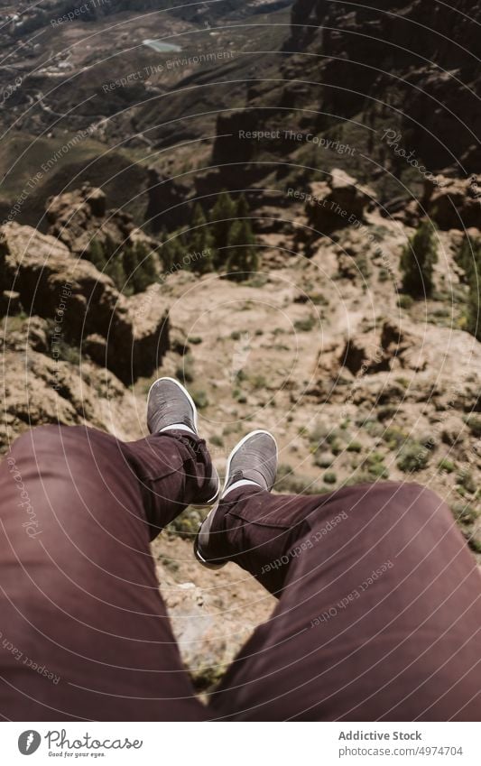crop view of feet hanging on a mountain first person edge hiking cliff hiker travel legs traveler shoes nature concept lifestyle green outdoor tourism high hill