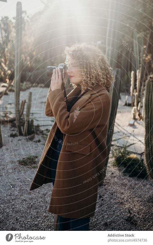 Portrait of beautiful curly blonde woman using a retro camera portrait model outdoors winter fashion face accessory apparel clothing coat confident cute elegant