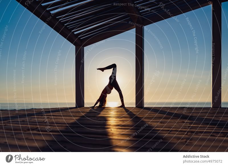 Flexible woman doing yoga on beach pose asana sunrise seaside stretch practice concentrate harmony healthy balance relax calm position peaceful morning body