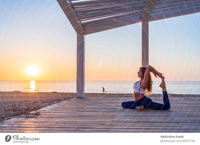 Flexible woman doing yoga in Mermaid pose on beach mermaid asana sunrise seaside stretch practice concentrate harmony healthy balance relax calm position