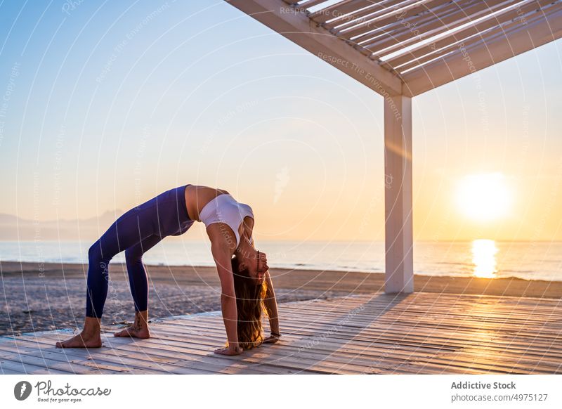 Flexible woman doing yoga on beach pose asana sunrise seaside stretch practice concentrate harmony healthy balance relax calm position peaceful morning body