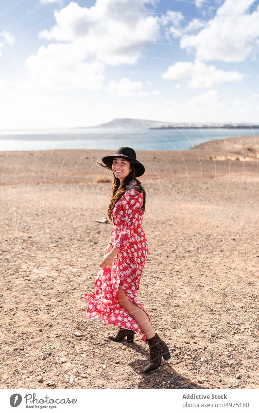 Stylish young ethnic woman at seaside follow me walk traveler fashion nature romantic trip holiday love together happy female long hair dark hair smile hat