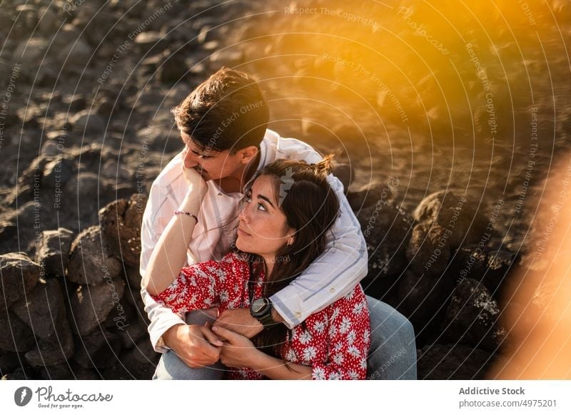 Relaxed young ethnic couple embracing on rocky coast cuddle relax seashore romantic together recreation style nature love relationship rest bonding boyfriend