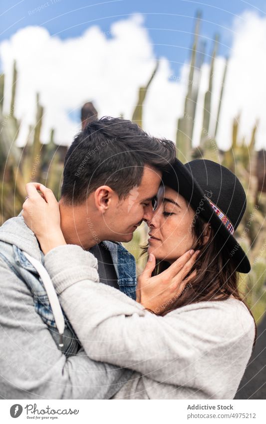 Romantic young ethnic couple standing in cactus garden during trip in Lanzarote holding hands romantic plant exotic relax love relationship together boyfriend