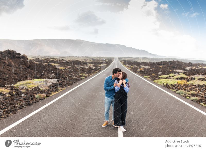 Young stylish couple embraced and walking on road in highland together mountain nature relationship holiday traveler adventure vacation boyfriend girlfriend