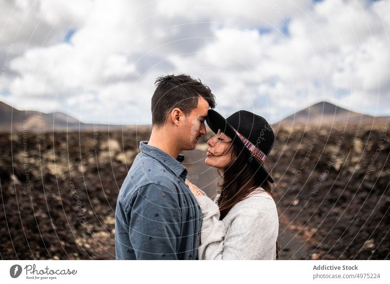 Cheerful young guy with her girlfriend in wild valley near volcanoes on Canary Islands couple hug love mountain vacation happy having fun relationship amorous