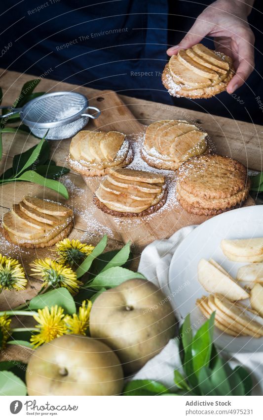 Crop person taking tartlet from table apple dessert kitchen home food fresh delicious meal tasty cookie yummy sieve biscuit gourmet nutrition tool icing