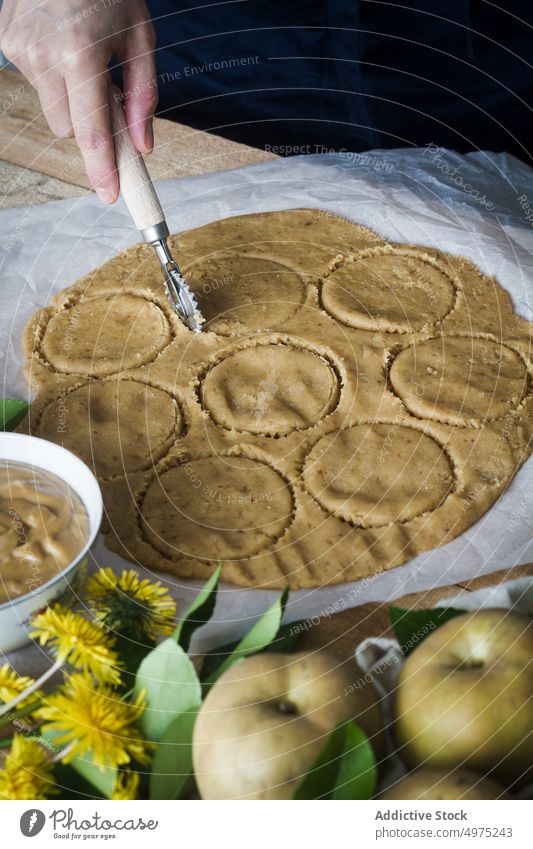 Crop person cutting circles from dough table cook pastry cutter tartlet apple fresh food dandelion prepare kitchen cuisine tradition sweet dessert recipe