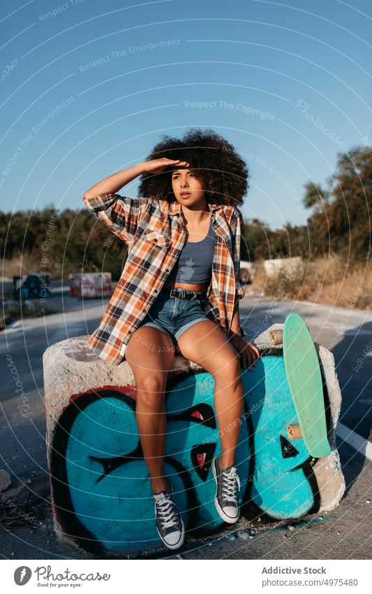 Tranquil African American woman with penny board on street summer skater cool millennial afro trendy tranquil hipster sunny female ethnic covering face