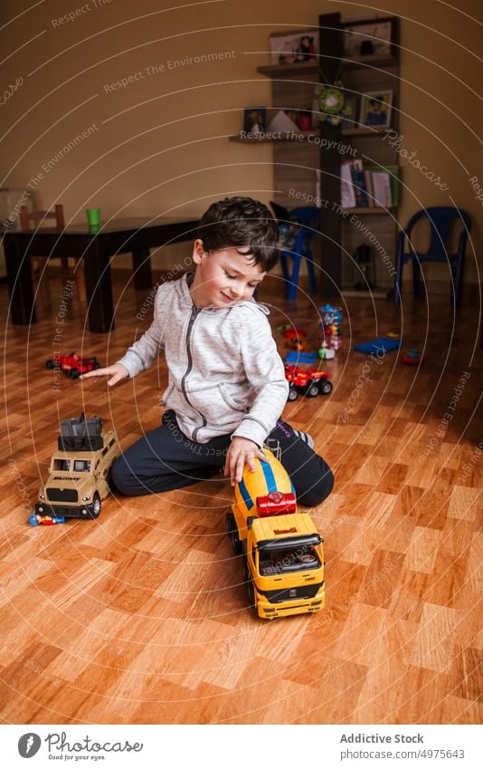 Happy boy playing with cars toy at home kid vehicle happy cheerful floor casual game little sit truck child male childhood playful entertain content recreation