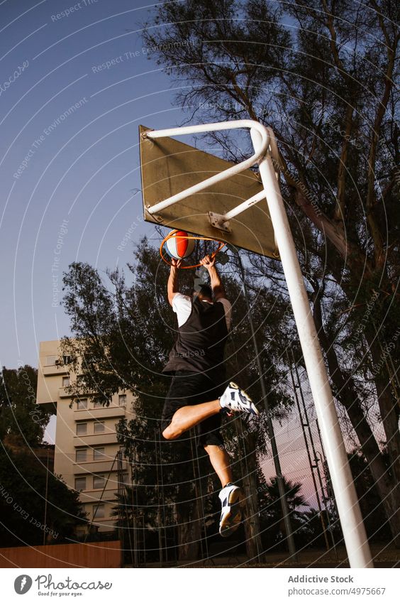 Strong determined man playing basketball on court at night dunk park jump shot hoop throw sports ground game slam dunk effort skill backboard success training