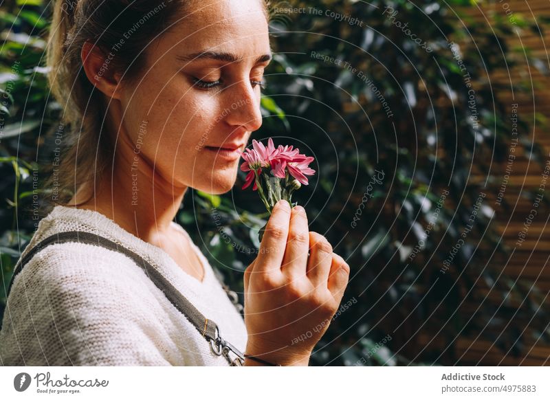 Young woman standing in orangery and smelling flower greenhouse daisy garden enjoy plant margarita grow work cultivate female young occupation profession owner