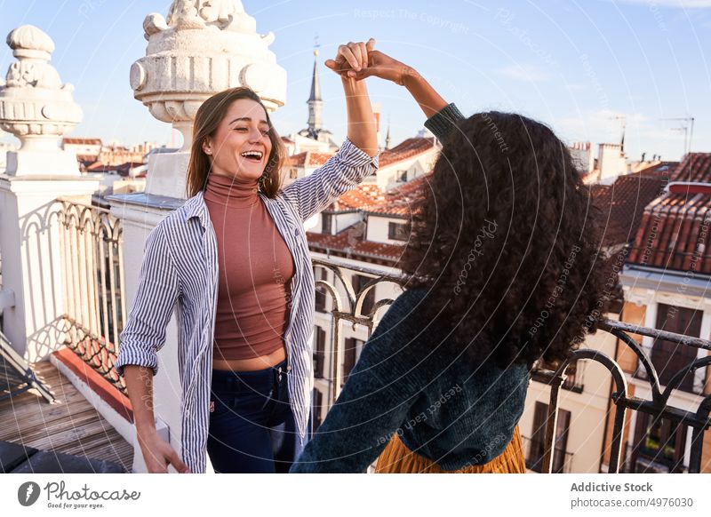 Joyful diverse women dancing on rooftop dance holding hands friend excited cheerful terrace joyful having fun carefree casual happy young together lifestyle